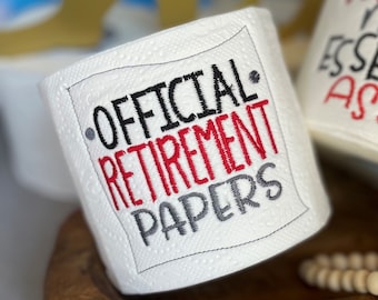 May include: A white toilet paper roll with the text "OFFICIAL RETIREMENT PAPERS" embroidered on it in black, red, and gray thread.