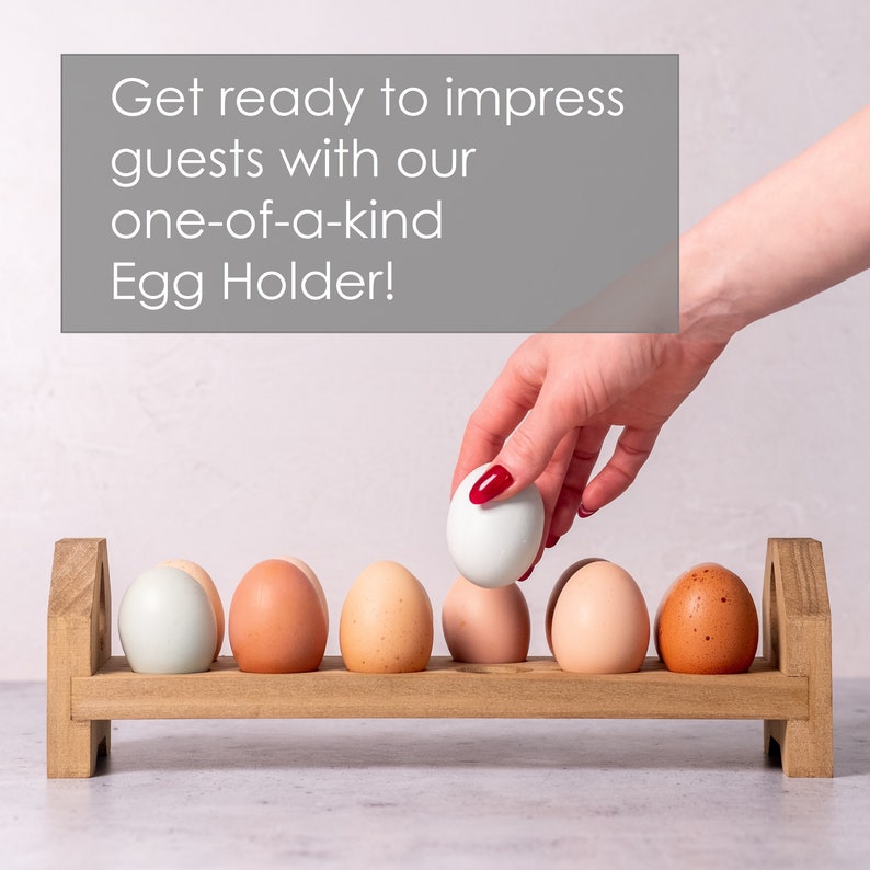 May include: A wooden egg holder with six brown eggs and one white egg. A hand is placing the white egg into the holder. The text "Get ready to impress guests with our one-of-a-kind Egg Holder!" is displayed above the holder.