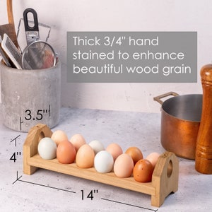 May include: Wooden egg holder with 10 slots, stained to enhance the wood grain. The holder is 14 inches long, 4 inches high, and 3.5 inches wide.