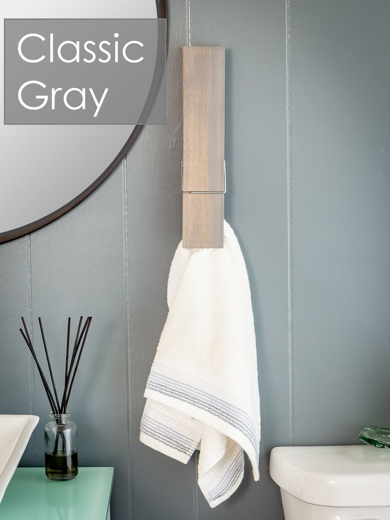 Puede incluir: Una toalla blanca con rayas grises cuelga de un toallero de madera con un clip de metal. El toallero est&aacute; montado en una pared gris. El texto "Classic Gray" es visible en la esquina superior izquierda de la imagen.