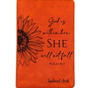 Op de afbeelding: Oranje leren gebonden notitieboek met een zwarte zonnebloem illustratie en de tekst: "God is in haar. ZIJ zal niet vallen. PSALM 46:5. Inshaal Arib."