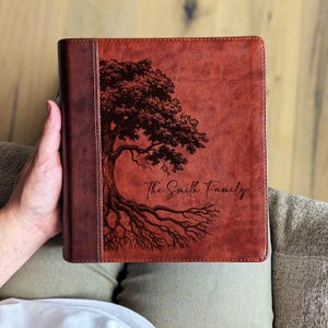 Puede incluir: Un diario de cuero marr&oacute;n con un dise&ntilde;o de &aacute;rbol y el texto "The Smith Family". El diario tiene un lomo marr&oacute;n oscuro. El dise&ntilde;o del &aacute;rbol es marr&oacute;n oscuro.