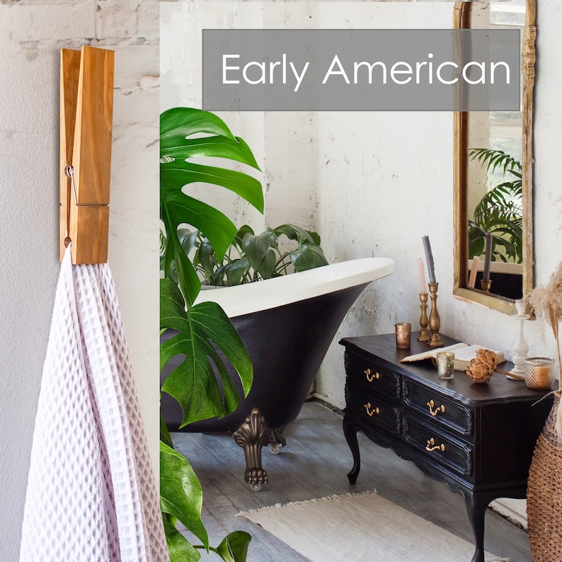 Puede incluir: Una ba&ntilde;era de patas de garra negra con interior blanco en un ba&ntilde;o con una gran planta verde, un toallero de madera con una toalla blanca colgada, una c&oacute;moda negra con tiradores dorados y un espejo dorado con el texto "Early American" encima.