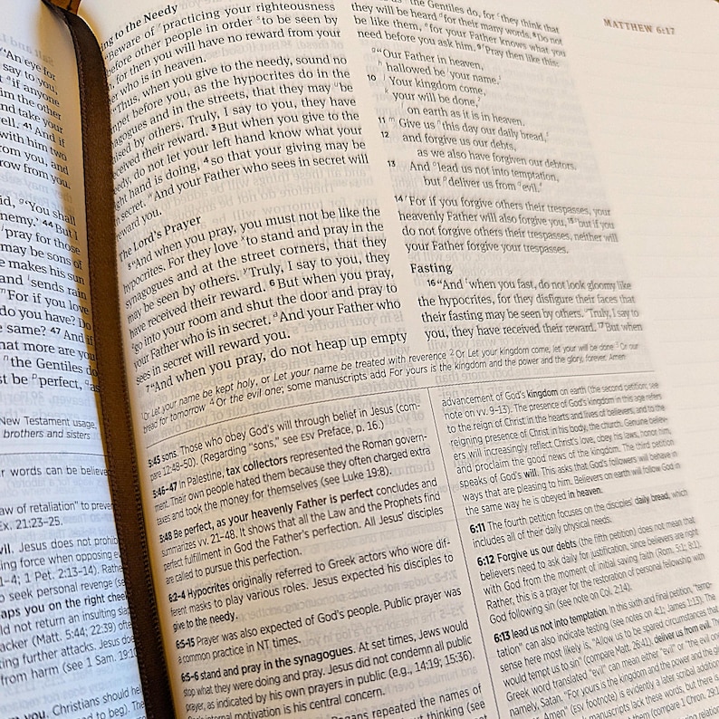 Puede incluir: Biblia abierta con texto de Mateo 6:1-17, sobre la oraci&oacute;n y la justicia. Las p&aacute;ginas est&aacute;n amarillentas, con una cinta de marcador marr&oacute;n. El texto es negro, con algunas anotaciones.