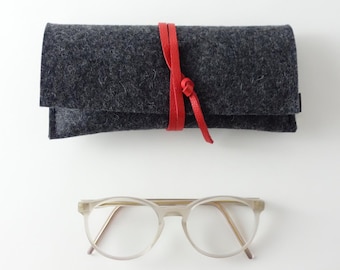 Minimalist glasses case made of pure organic wool felt in anthracite with a closure strap made of organic leather in various colors