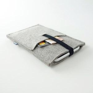 May include: A gray felt phone case with a black elastic band and a pocket for cards. The case is holding a smartphone and a credit card.