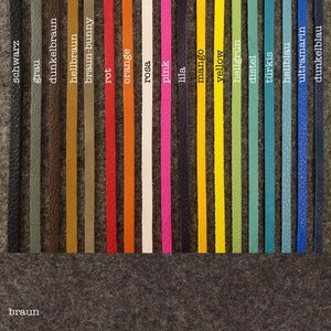 May include: A variety of leather cord colors, including black, gray, brown, red, orange, pink, purple, mango, yellow, green, blue, and teal. The colors are arranged in a row on a gray felt background.