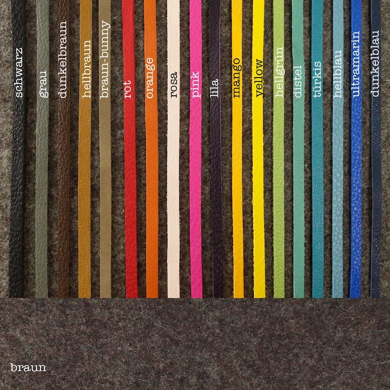 May include: A variety of leather cord colors, including black, gray, brown, red, orange, pink, purple, mango, yellow, green, blue, and teal. The colors are arranged in a row on a gray felt background.