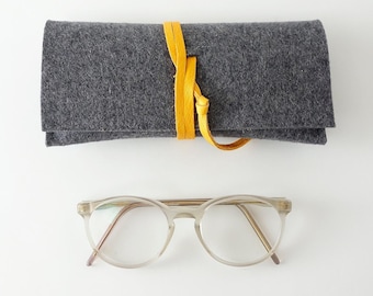 Minimalist glasses case made of pure organic wool felt dark gray with closure strap made of organic leather strap in different colors