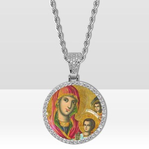 May include: Silver pendant necklace with a religious icon depicting a woman in a red head covering and a child. The round pendant is edged with small, clear stones and suspended from a rope chain.