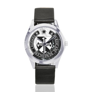 May include: A silver wristwatch with a black leather band. The watch face features a black and white emblem with the words "LAUDARE", "BENEDICERE", and "PRAEDICARE" in black text. The watch has a marble-like background.