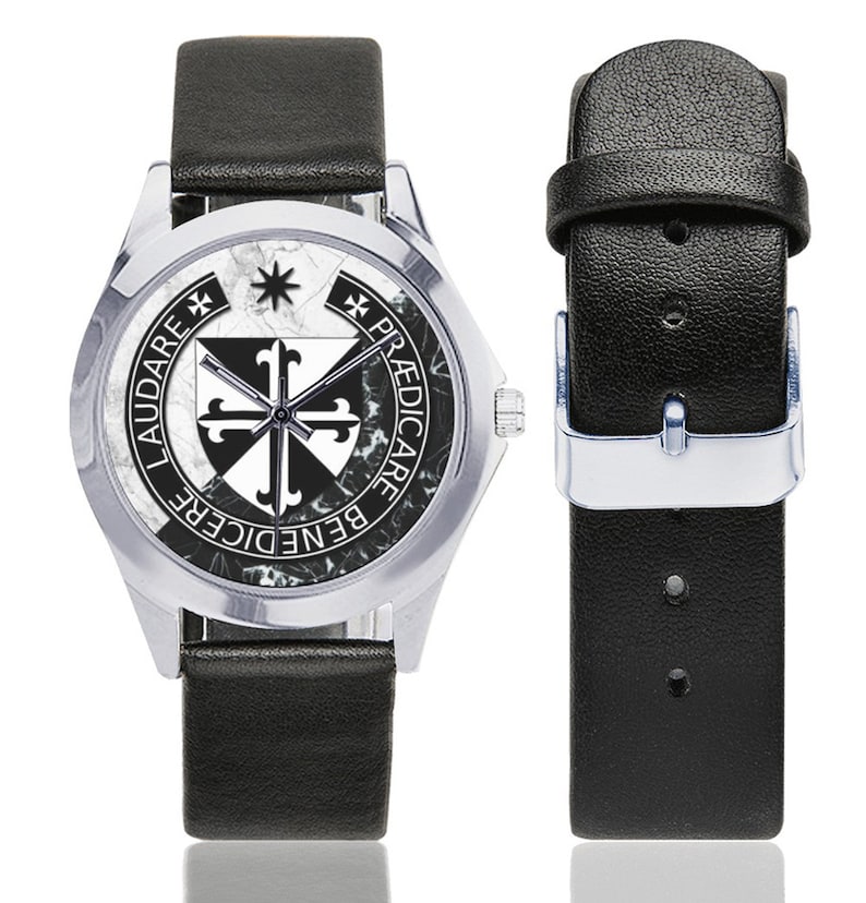 May include: A silver-toned wristwatch with a black leather band. The watch face features a black and white emblem with the words "LAUDARE BENEDICERE PREDICARE". The watch band is shown separately with a silver buckle.