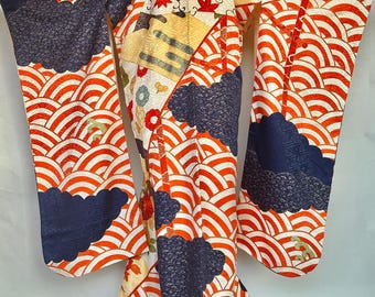 May include: A traditional Japanese kimono with a vibrant design. The kimono features a pattern of red and white waves, navy blue cloud-like shapes, and floral and leaf motifs. The sleeves and hem are trimmed with navy blue fabric.