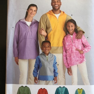 May include: Simplicity pattern R11340 for hooded pullovers. The pattern features a family wearing different colored pullovers: purple, yellow, pink, and blue. The pattern includes sizes XS-XL. Designed and printed in the USA.