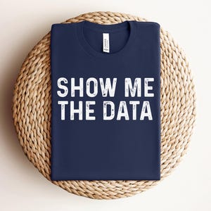 May include: A navy blue t-shirt with the text "Show Me The Data" in white lettering.