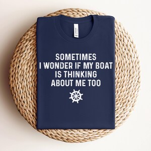 May include: A navy blue t-shirt with white text that reads "Sometimes I wonder if my boat is thinking about me too." A white ship's wheel graphic is below the text.