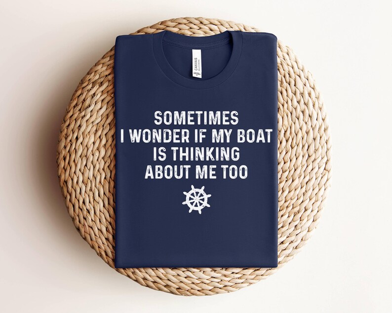 May include: A navy blue t-shirt with white text that reads "Sometimes I wonder if my boat is thinking about me too." A white ship's wheel graphic is below the text.
