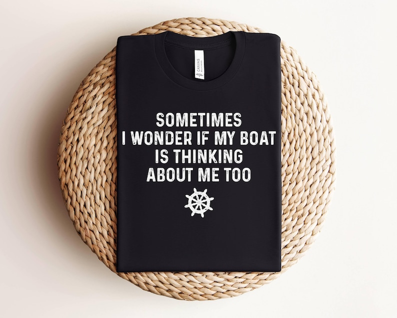 May include: Black t-shirt with white text that reads "Sometimes I wonder if my boat is thinking about me too." A white steering wheel icon is below the text.