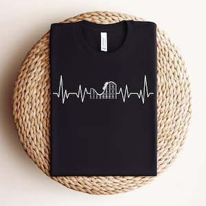 May include: Black t-shirt with a white graphic of a roller coaster inside a heartbeat. The graphic is a simple line drawing.