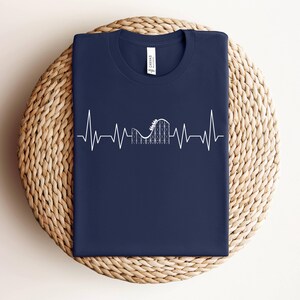 May include: A navy blue t-shirt with a white graphic of a roller coaster inside a heartbeat.