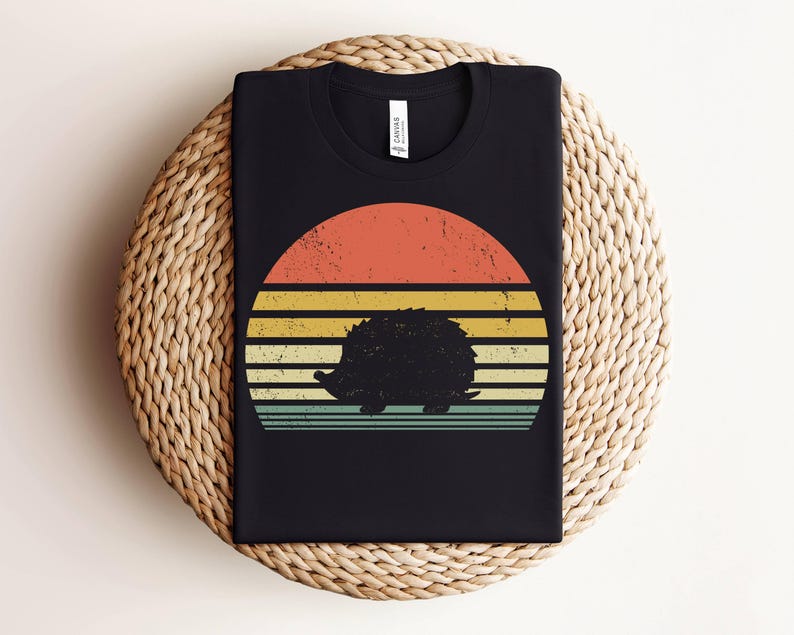 K&ouml;nnte beinhalten: Schwarzes T-Shirt mit einem Retro-Sonnenuntergangsdesign mit einer Silhouette eines Igels. Der Sonnenuntergang hat orange, gelbe und blaue Streifen.
