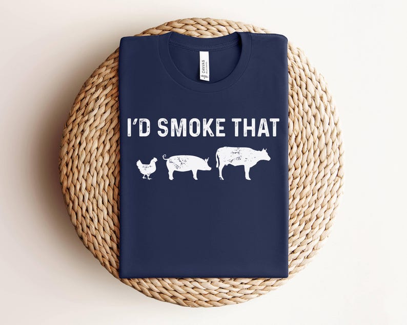 K&ouml;nnte beinhalten: Ein marineblaues T-Shirt mit dem Text "I'd Smoke That" in Wei&szlig;. Das Shirt zeigt eine wei&szlig;e Silhouette eines Huhns, eines Schweins und einer Kuh.