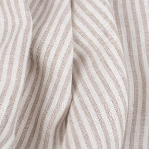 Könnte beinhalten: Nahaufnahme eines beige-weiß gestreiften Stoffes mit subtiler Textur. Der Stoff ist gefaltet und zeigt die Webart des Materials.