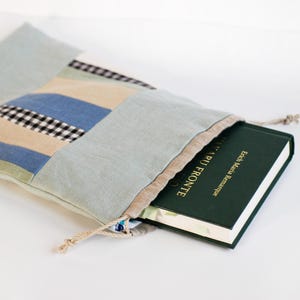 May include: A blue and white patchwork fabric drawstring bag with a book titled "Erich Maria Remarque All Quiet on the Western Front" inside.