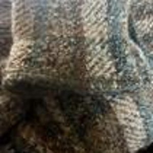 May include: A thick, textured fabric featuring a prominent herringbone weave pattern in shades of charcoal gray, slate blue, and earthy brown. The material displays a dense, multi-tonal appearance with visible interlacing fibers throughout the surface.