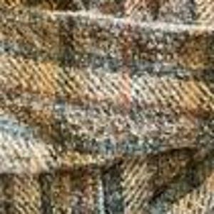 May include: A close-up view of a woven fabric featuring a textured herringbone pattern in shades of brown, tan, and charcoal gray. The material displays a dense, interlaced weave with visible fibers and a multi-tonal appearance throughout the surface.