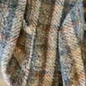 May include: A close-up view of a woven fabric featuring a textured pattern of vertical stripes in shades of brown, tan, gray, and cream. The material displays a distinct diagonal twill weave with visible fibers and a multi-colored, speckled appearance.