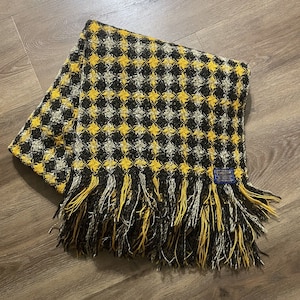 May include: A yellow and black checkered throw blanket with fringe. The blanket has a blue label with the text "Pendleton."