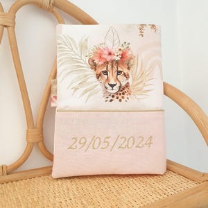 May include: A pink and white pillow with a cheetah wearing a flower crown and a date embroidered on the bottom. The date is 29/05/2024.