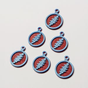 May include: Six blue and red pendants featuring a lightning bolt design. Each pendant has a blue outline and a red center with a blue lightning bolt. The pendants are circular with a small loop at the top.