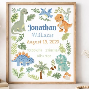 May include: A framed cross-stitch with a dinosaur theme, personalized with the name "Jonathan Williams" and birth details. The design includes several dinosaurs, foliage, and the date August 15, 2025, 10:55 am, 53 cm, and 4.08 kg.