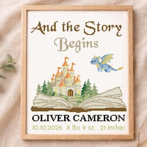 May include: A framed cross-stitch artwork with the text "And the Story Begins." It features a castle, a dragon, and the name "OLIVER CAMERON" with birth details: 10.10.2026, 8 lbs 9 oz, and 21 inches.