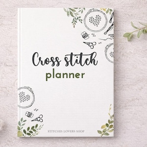 Puede incluir: Un planificador de punto de cruz blanco con las palabras "Cross stitch planner" en escritura negra. La portada presenta ilustraciones de herramientas de punto de cruz y acentos florales. El nombre de la tienda "Stitches Lovers Shop" está en la parte inferior.