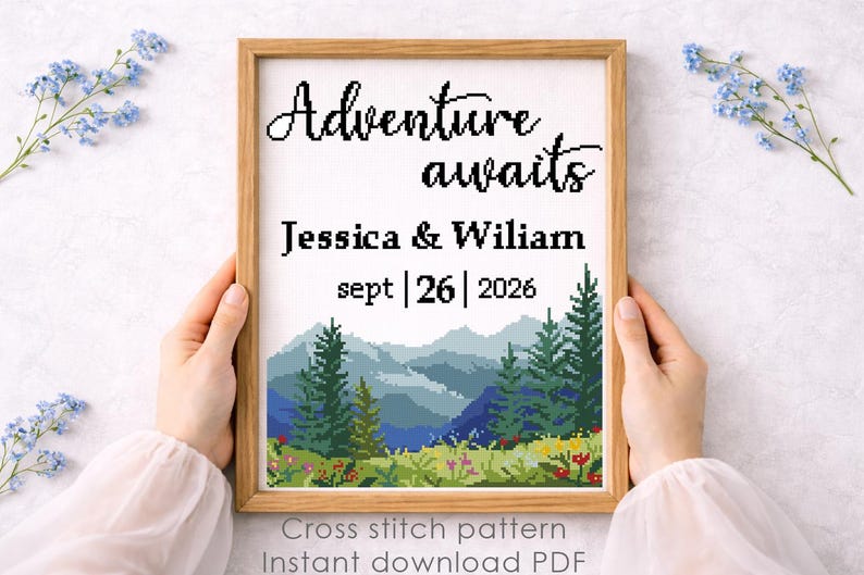 May include: A framed cross-stitch pattern with the words "Adventure awaits" above the names Jessica & Wiliam and the date Sept 26, 2026. The design features a mountain landscape with trees and flowers. Text at the bottom reads "Cross stitch pattern Instant download PDF."