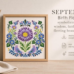 May include: A framed cross-stitch pattern featuring a floral design with a large purple flower at the center, surrounded by blue and green accents. The text reads "SEPTEMBER Birth Flowers".