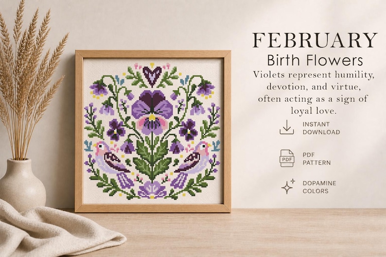 May include: A framed cross-stitch pattern featuring a floral design with violets and birds in shades of purple, green, and pink. The text reads "FEBRUARY Birth Flowers" and describes violets as symbols of humility and devotion.
