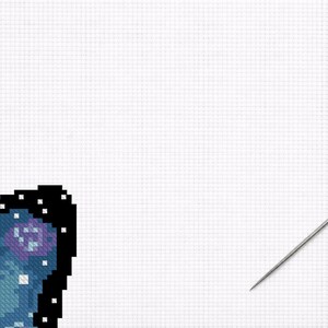 Puede incluir: Un proyecto de punto de cruz en progreso, con un ala de mariposa pixelada con un dise&ntilde;o celestial en tonos azules, morados y blancos. Una aguja est&aacute; colocada a la derecha, lista para coser sobre la tela de rejilla blanca.