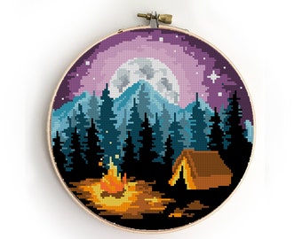Peut inclure: Motif de point de croix représentant une scène nocturne avec une pleine lune, des montagnes, des arbres, un feu de camp et une tente. Le ciel est violet et bleu avec des étoiles.