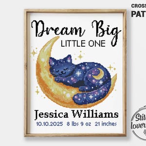 Pode incluir: Padrão de ponto cruz emoldurado com um gato dormindo em uma lua crescente. O gato é azul escuro com um design estrelado. O texto diz "Dream Big Little One" e inclui um nome, data, peso (3,9 kg) e altura (53 cm).