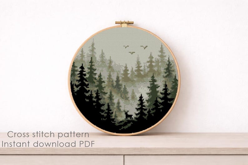 May include: A cross-stitch pattern of a forest scene in a round wooden hoop. The design features dark green and black trees, a deer, and birds against a misty background. The text "Cross stitch pattern Instant download PDF" is at the bottom.