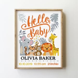May include: A framed cross-stitch design with a white background and colorful animals. The text "Hello Baby" is in orange cursive lettering. The animals include a giraffe, elephant, tiger, and monkey. The name "Olivia Baker" is below the animals, along with the date "10.10.2019", time "10:55 am", and measurement "21 inches".
