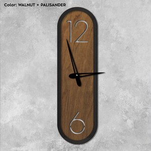 Pu&ograve; includere: Un orologio ovale in legno con cornice nera e numeri argentati. Il quadrante dell'orologio ha una finitura in legno di noce e palissandro.