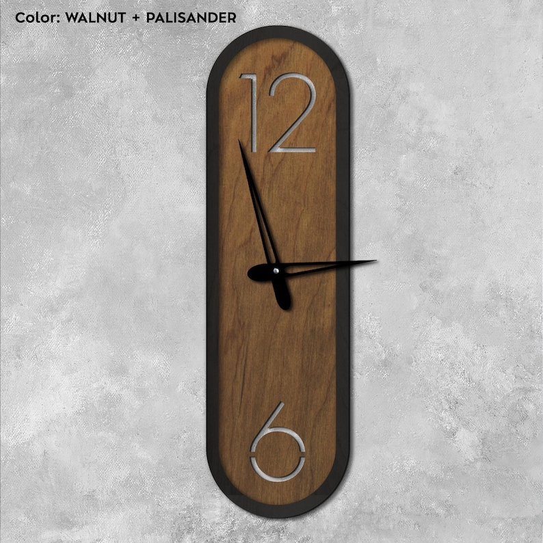 Pu&ograve; includere: Un orologio ovale in legno con cornice nera e numeri argentati. Il quadrante dell'orologio ha una finitura in legno di noce e palissandro.