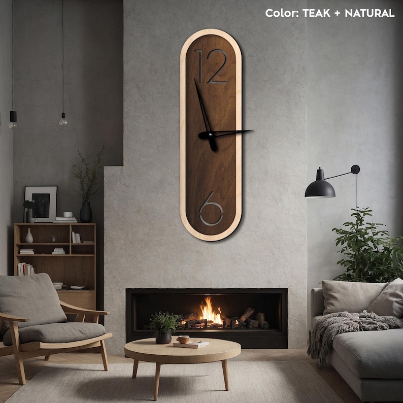 Pu&ograve; includere: Un orologio da parete moderno con finitura in teak e legno naturale. Il quadrante dell'orologio &egrave; di forma ovale con lancette nere e numeri bianchi. L'orologio &egrave; appeso a una parete grigia in un soggiorno.