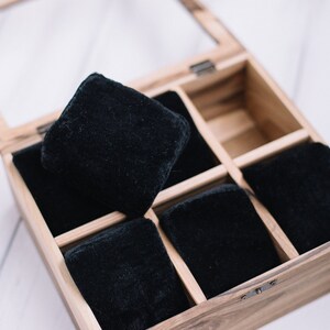 May include: A wooden watch box with a glass lid, containing six black velvet watch cushions.