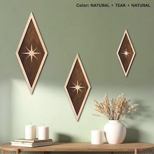 Puede incluir: Tres piezas de decoración de pared de madera en forma de diamante con un diseño de estrella en el centro. La decoración es en tonos de madera natural con un acento de madera de teca. La decoración está colgada en una pared verde claro.